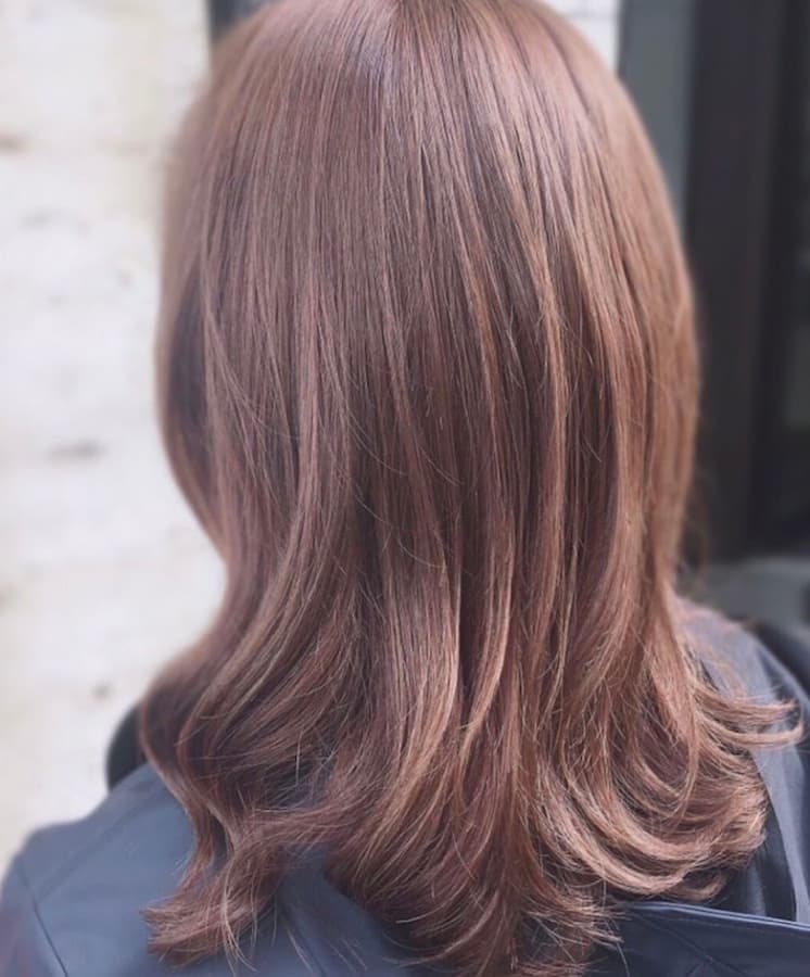 Back view of a woman with ash brown hair, freshly colored in a hair salon in Düsseldorf.
